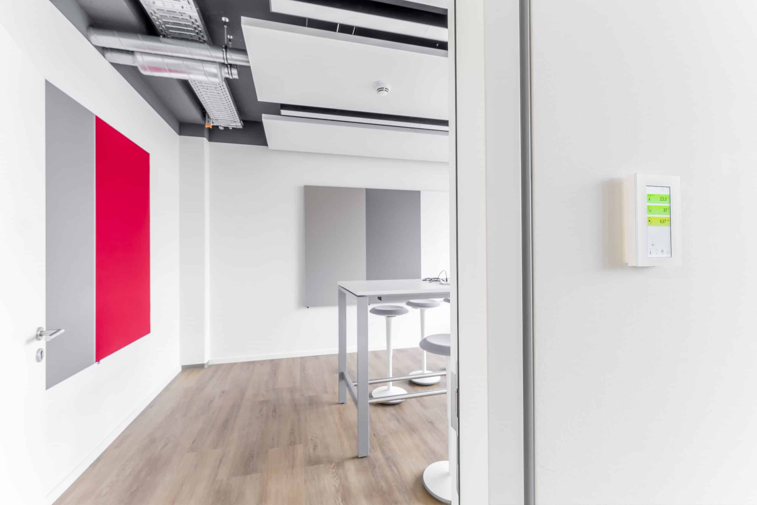 Thermokon zeigt das an der Wand montierte Raumbedienelement eines Besprechungsraumes mit Display.