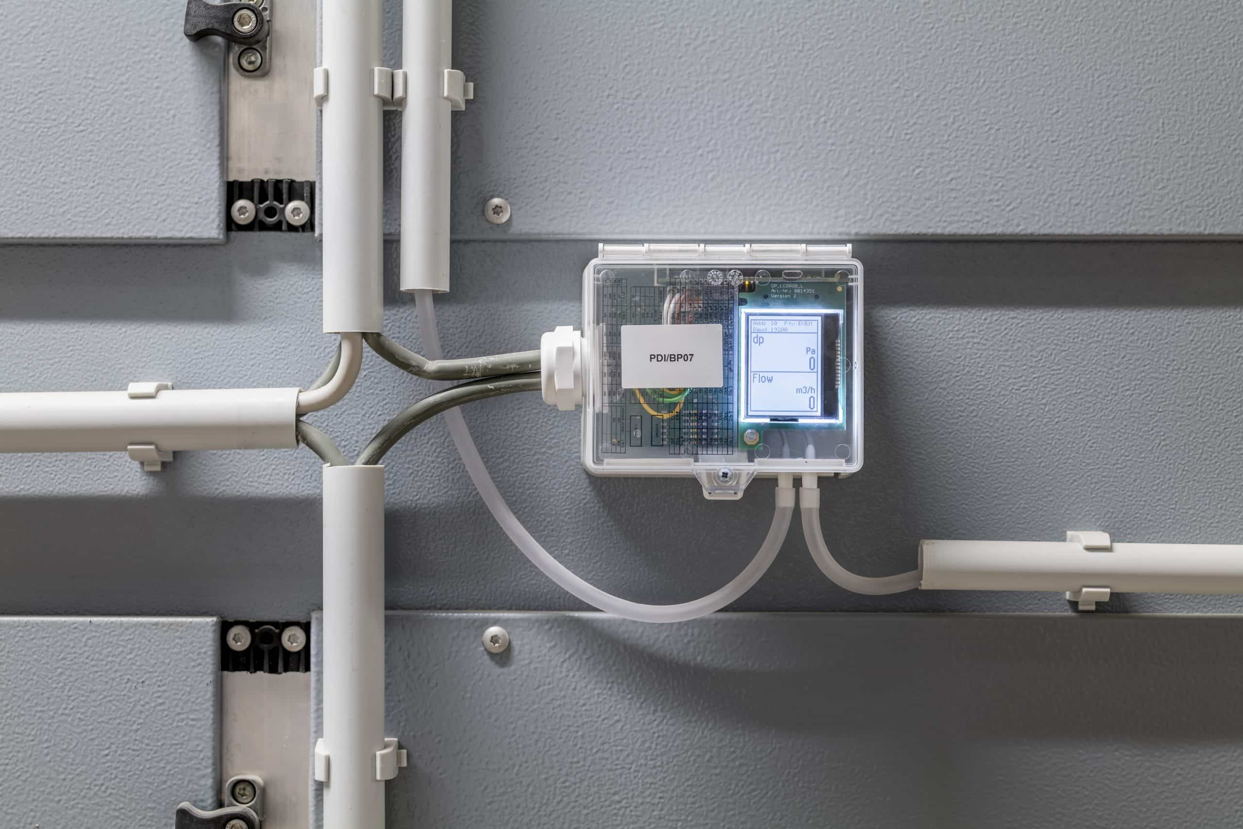 Thermokon zeigt die Detailaufnahme eines Steuerelements im Heizungsraum eines Bürogebäudes mit beleuchtetem Display.