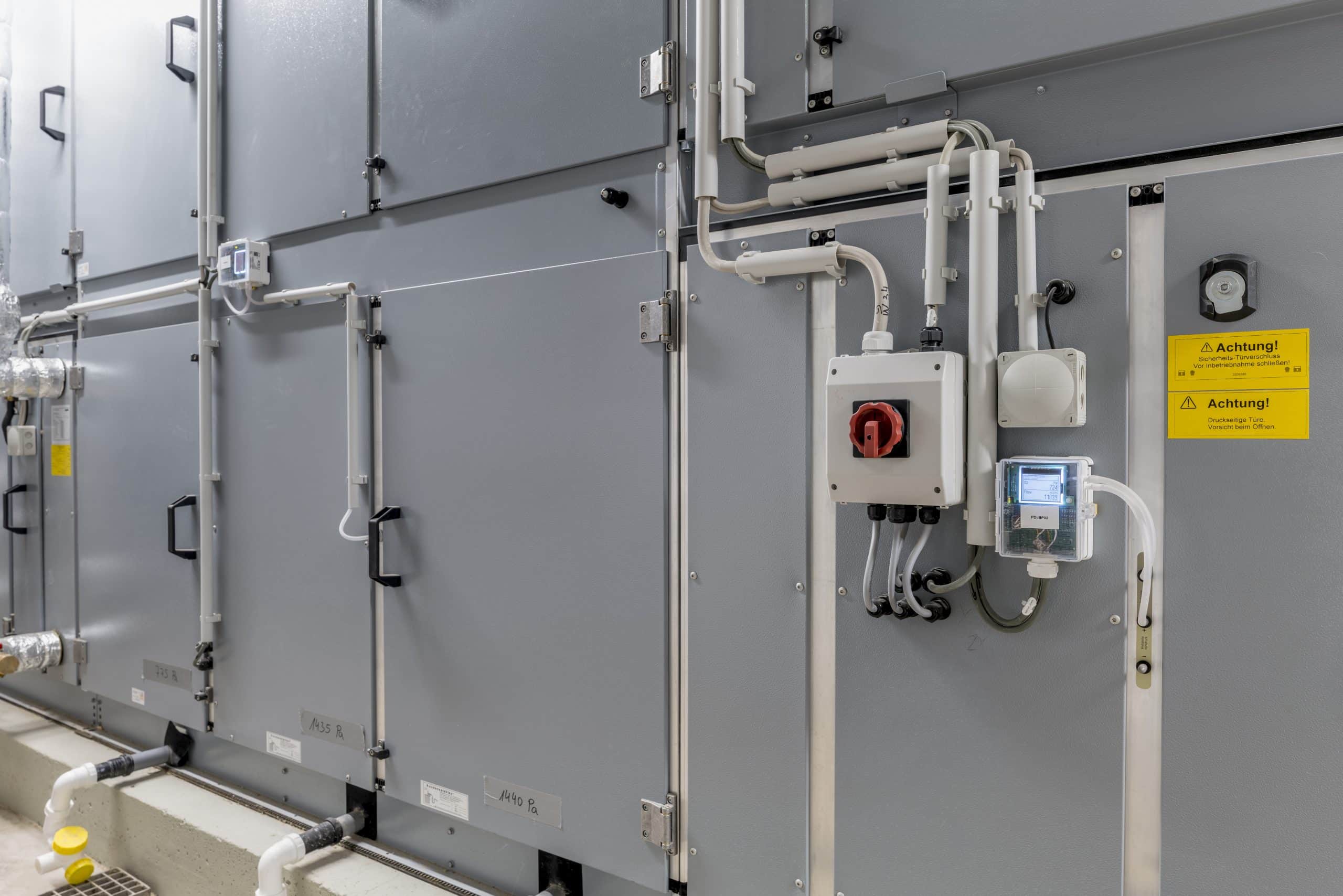 Thermokon zeigt die verlegten Leitungen und ein Steuerelement im Heizungsraum eines Bürogebäudes.