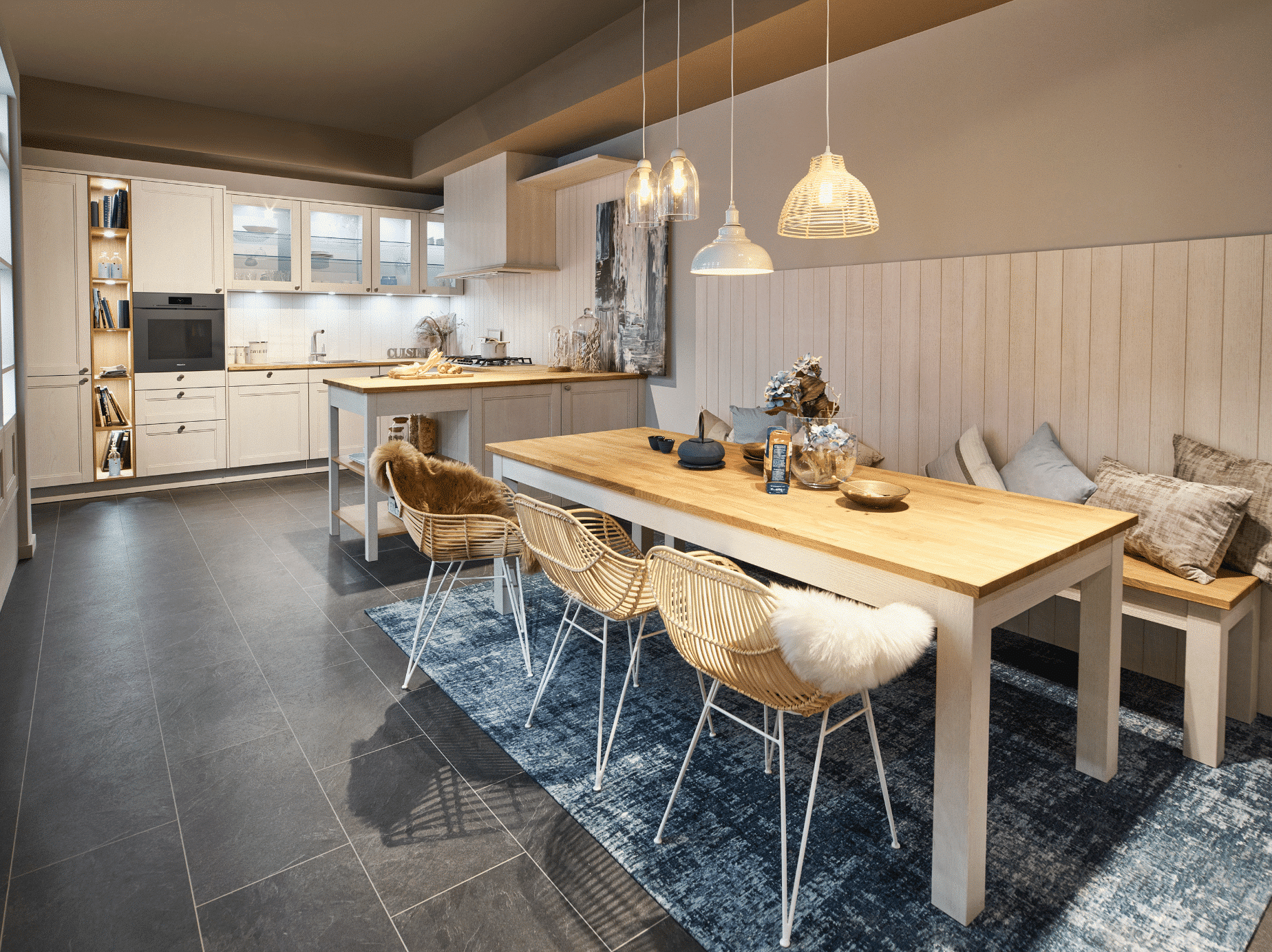 Bauer Tischlerei zeigt eine weisse Küche und einen Essbereich mit einem Holztisch, Stühlen und einer Sitzbank mit Polstern von Sachsenküchen.