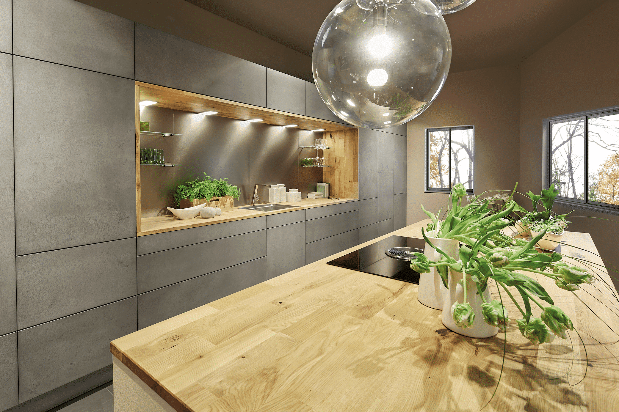 Bauer Tischlerei zeigt eine graue Küche in Betonoptik mit einer silbernen Spüle und einer Kochinsel aus Holz, mit einem Ceranfeld und einer runden Lampe von Sachsenküchen.