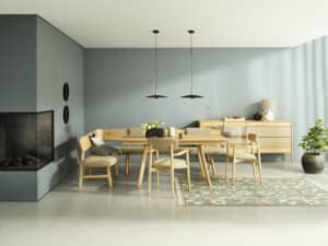 Ein offener Essbereich mit Kamin, hellem Massivholztisch, Eckbank, passenden Holzstühlen mit gepolsterten Sitzflächen und einem schlichten Sideboard von BAUER Tischlerei zeigt Anrei.