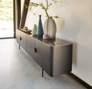 BAUER Tischlerei zeigt haas Möbelwerk mit einer dunklen Holzkommode im Stil der 60er Jahre mit einer Ablagefläche in dunkelbrauner Marmoroptik und kunstvollen Tonvasen, modern interpretiert - KI - modifiziert.