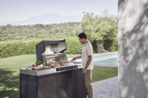 BAUER Tischlerei zeigt einen Mann am Grill seiner Fire Pro iQ Outdoorküche von Miele.