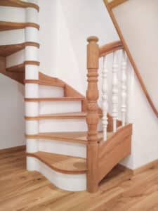 Wendeltreppe mit Auftritt, Handlauf und Wange aus Vollholz und gedrechselten Ballustraden in Weiss von Tischlerei Penninger.