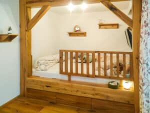 Ein Kinderzimmer mit einer rustikalen massiv verbauten Schlafkoje mit Gitterbettfunktion aus Vollholz von Tischlerei Penninger.