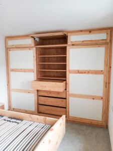 Schlafzimmer mit eingemauertem deckenhohen Wandschrank aus Vollholz mit weissen Kassetten von Tischlerei Penninger.