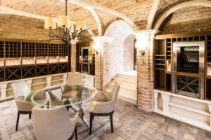 Gemauerter Weinkeller mit Gewölbe und verbauten Wandnischen aus Weinregalen und Weintemperierschränken aus dunklem Holz von Tischlerei Penninger.