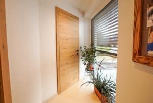 Tischlerei Scharnreithner zeigt einen Flur mit Holztüre mit matt schwarzen Griffen.