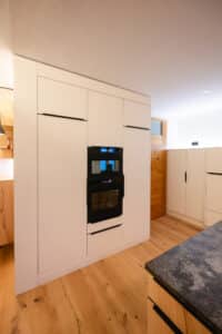 Eine moderne Küche mit weißer Gerätezeile mit filigranen mattschwarzen Griffen in minimalistischer Optik von Tischlerei Scharnreitner.