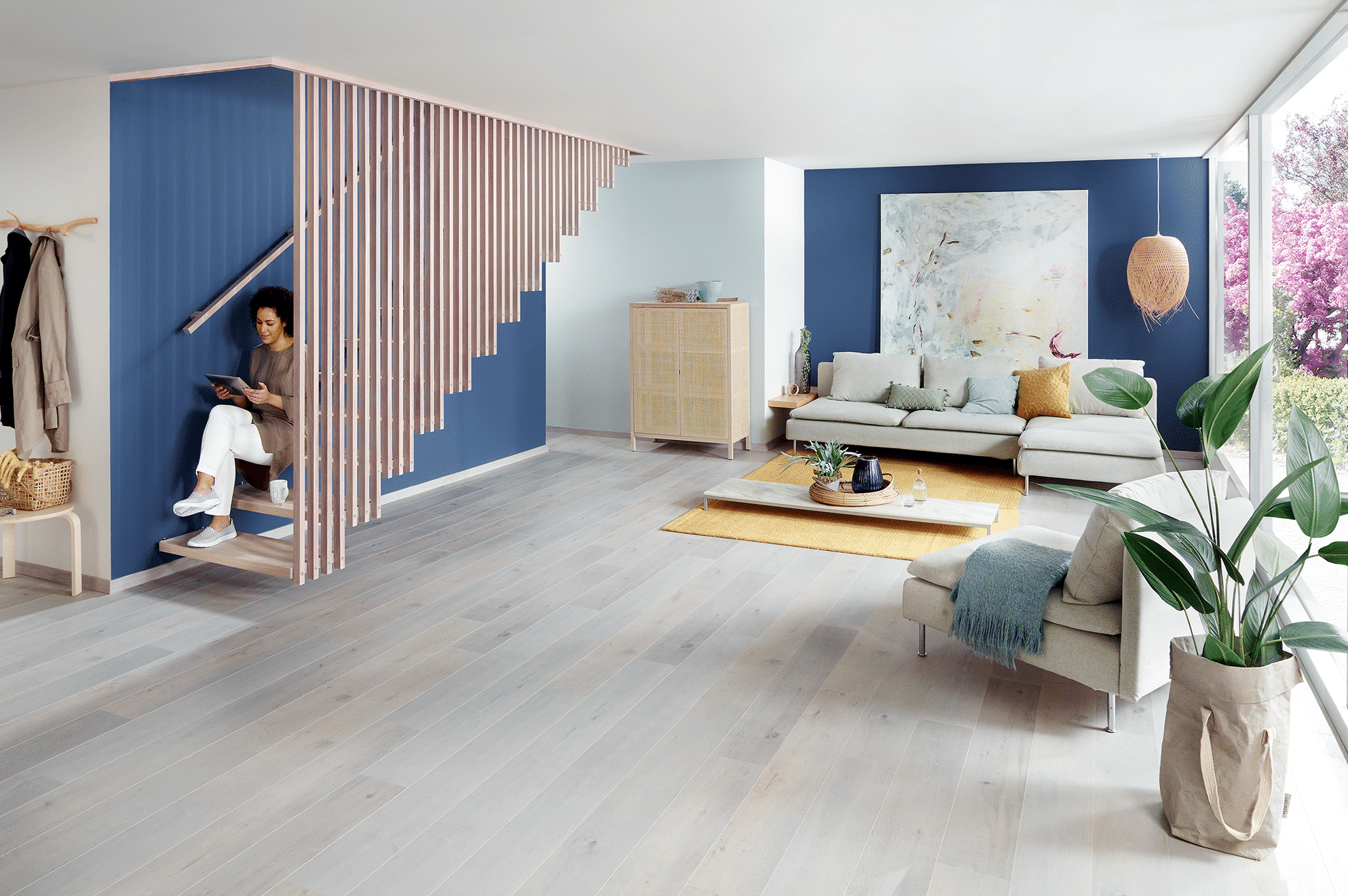 Treppenmeister zeigt freiliegende Holztreppe mit Holz-Handlauf an der Wand und Geländer aus Holzsprossen, die von den Trittflächen bis nach oben verlaufen.