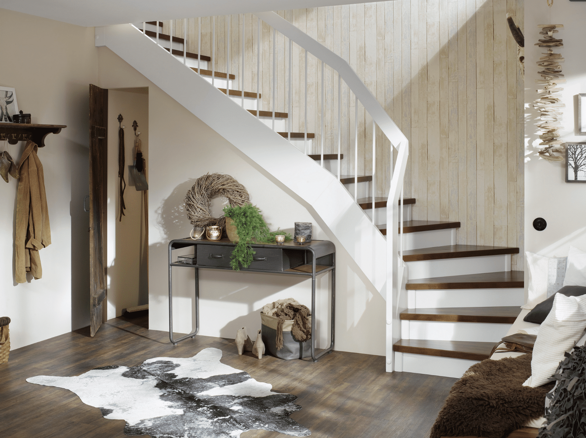 Treppenmeister zeigt gedrehte Holztreppe mit weißem Holzhandlauf, weißen Treppenfronten und Trittflächen aus dunklem Holz mit verstecktem Stauraum unter der Treppe an einer rustikal Holzverkleideten Wand.