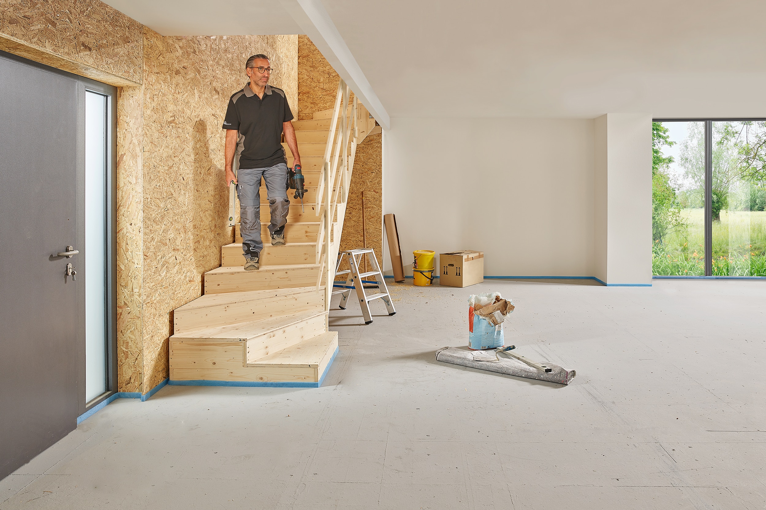 Ein Handwerker beim Arbeiten an der Rohversion einer Treppe mit Stauraum von Treppenmeister.