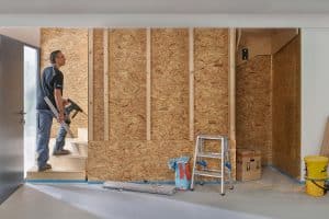 Ein Handwerker arbeitet an einer Treppe von Treppenmeister welche durch einen Wandverbau und die Integration des Untertreppenstauraums eine zusätzliche Abstellkammer bekommt.