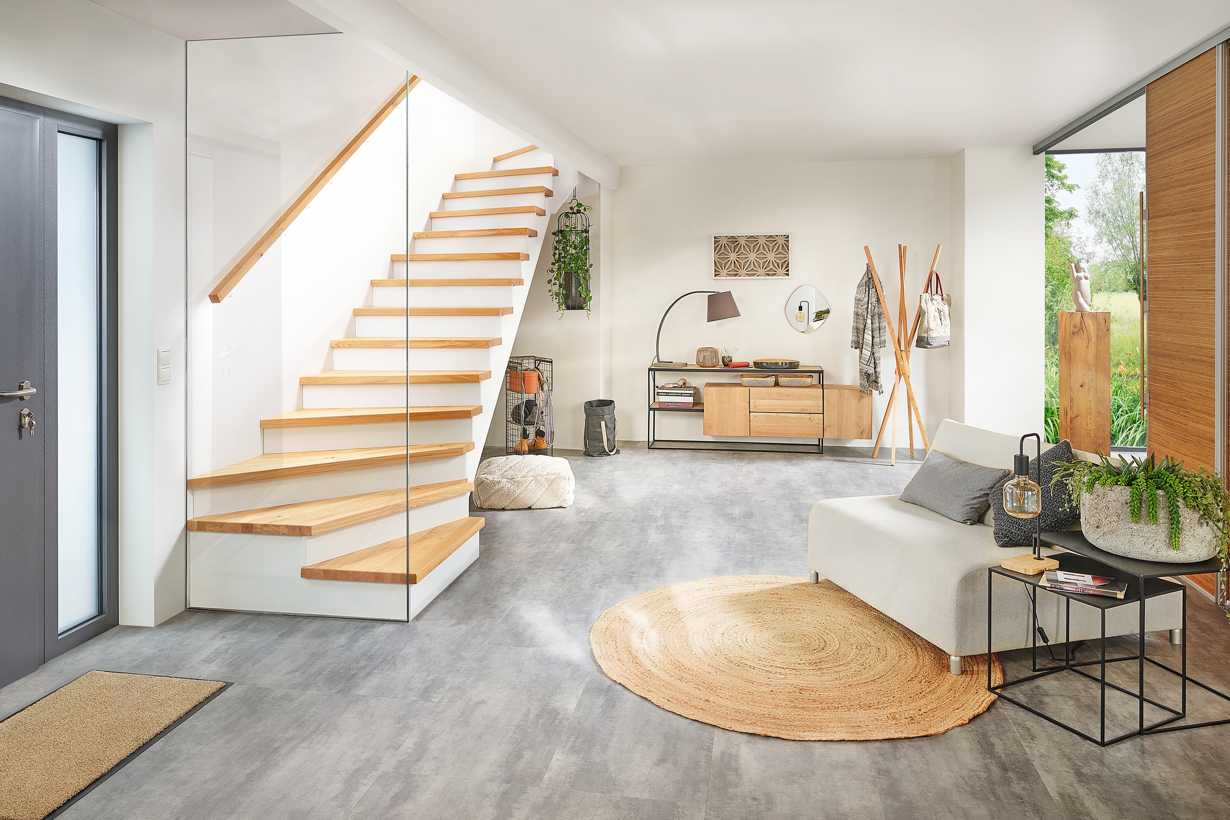 Eine Treppe mit Holzhandlauf, Holzauftritt, freizugänglichem Untertreppenstauraum und einer deckenhohen Glaswand am Treppenende von Treppenmeister.