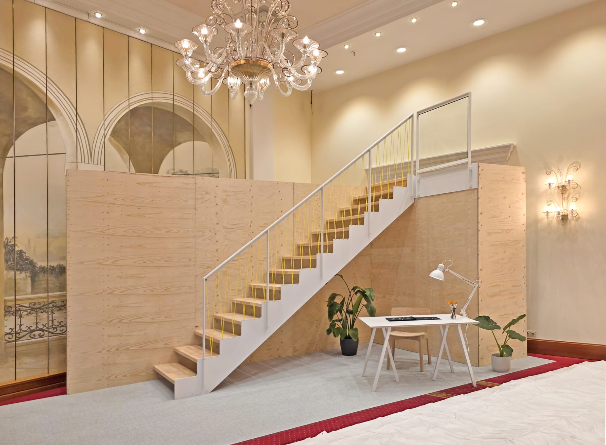 Ein Bühnenaufbau mit eleganter Schau­treppe aus Holz, metallischer Hand­laufstruktur und gelben Geländerstäben bei der Jubiläumstagung von Treppenmeister.