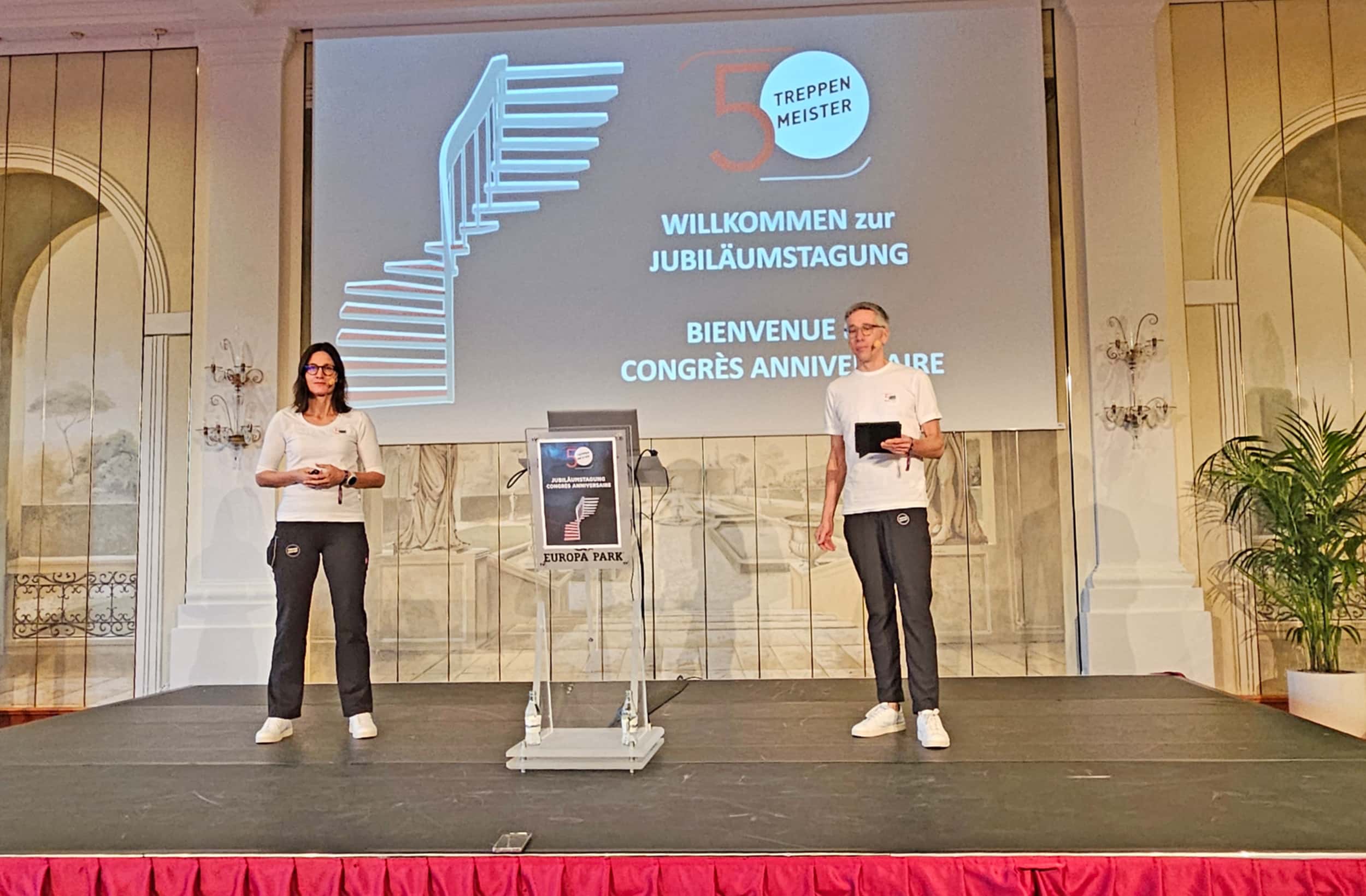 Geschäftsführer Andrea und Thomas Köcher auf der Bühne der Jubiläumstagung von Treppenmeister.