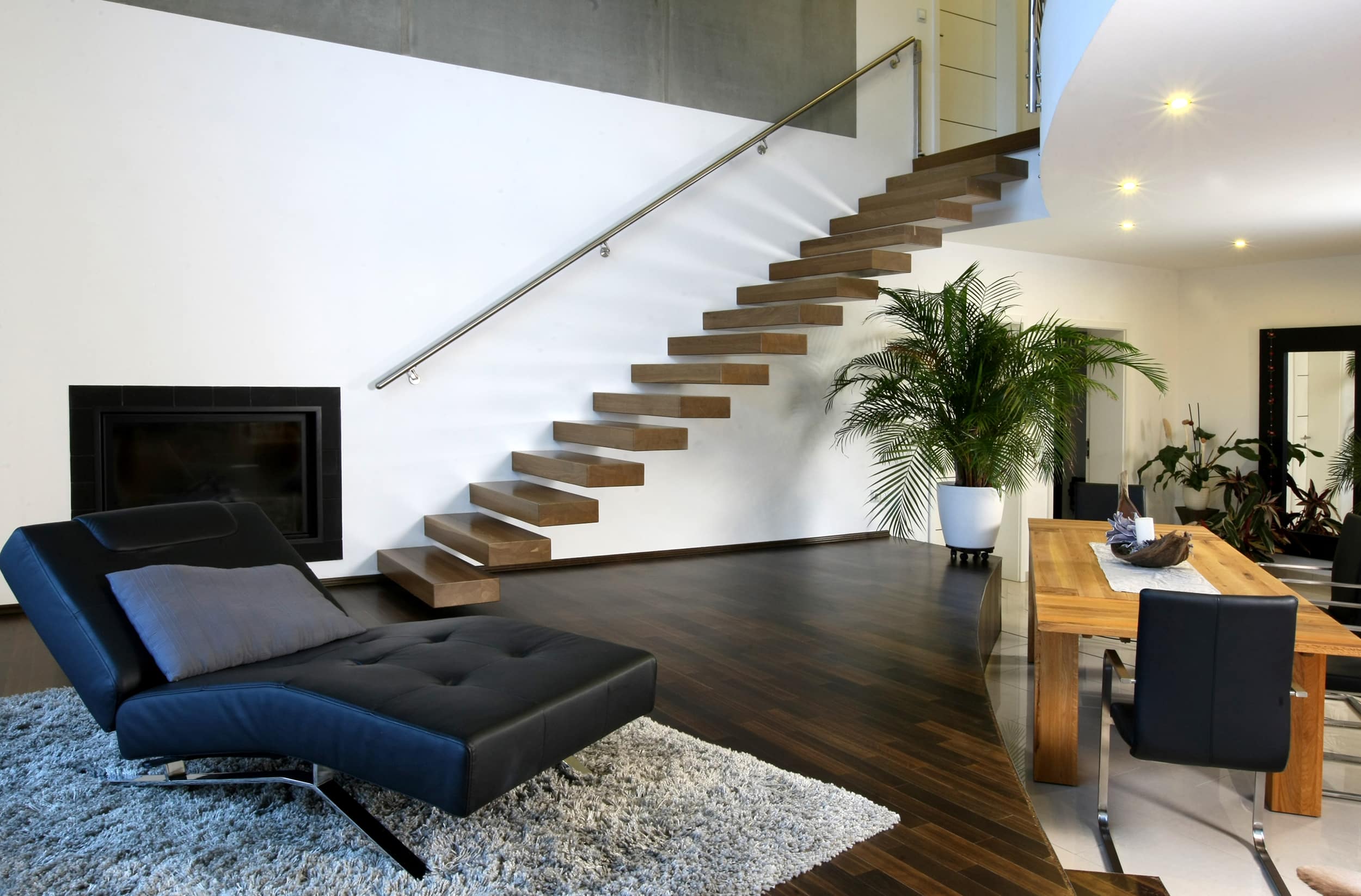 Moderne freischwebende Kragarmtreppe im Loftstil mit dunklen Holzstufen und wandseitigem Handlauf von Treppenmeister.