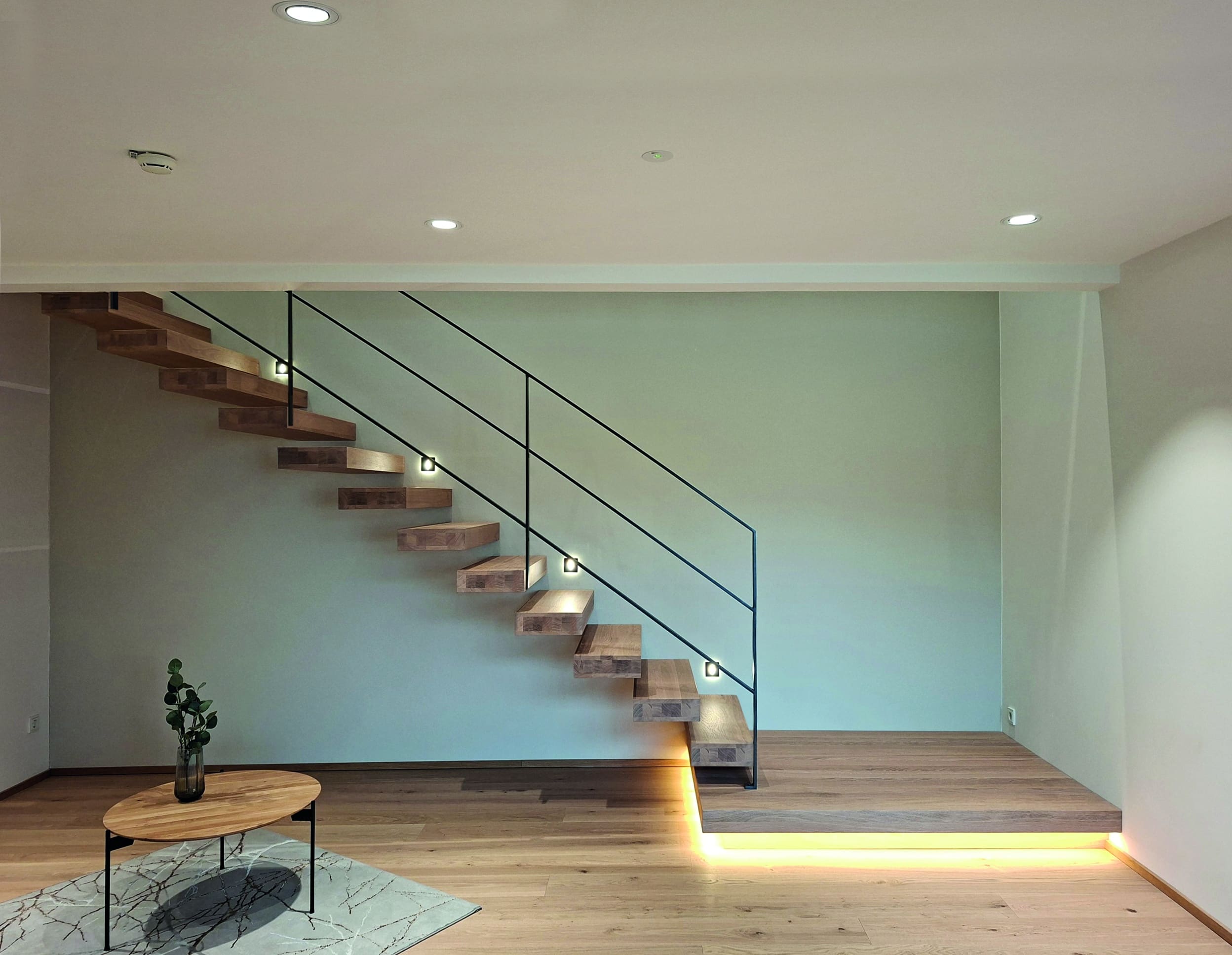 Moderne Kragarmtreppe im Industrial-Stil mit Holzstufen und schwarzem Eisenhandlauf in klarer Linienführung von Treppenmeister.