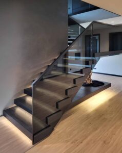 Moderne schwebende Kragarmtreppe mit schwarzen von unten beleuchteten Holzstufen mit Rauchglasgeländer in minimalistischem Design von Treppenmeister.