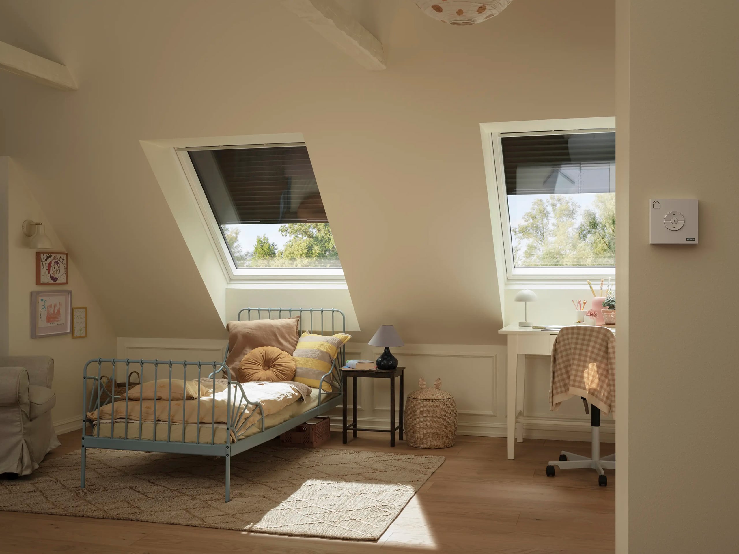 Velux zeigt zwei geschlossene Dachfenster in einem Kinderzimmer mit Rollladen-System, das optimal vor Sonneneinstrahlung und Hitzeentwicklung schützt.