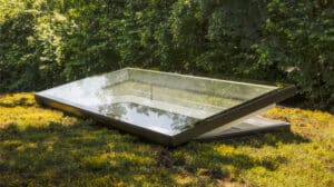 VELUX zeigt ein geöffnetes dunkelgraues Flachglasfenster auf einem begrünten Flachdach.