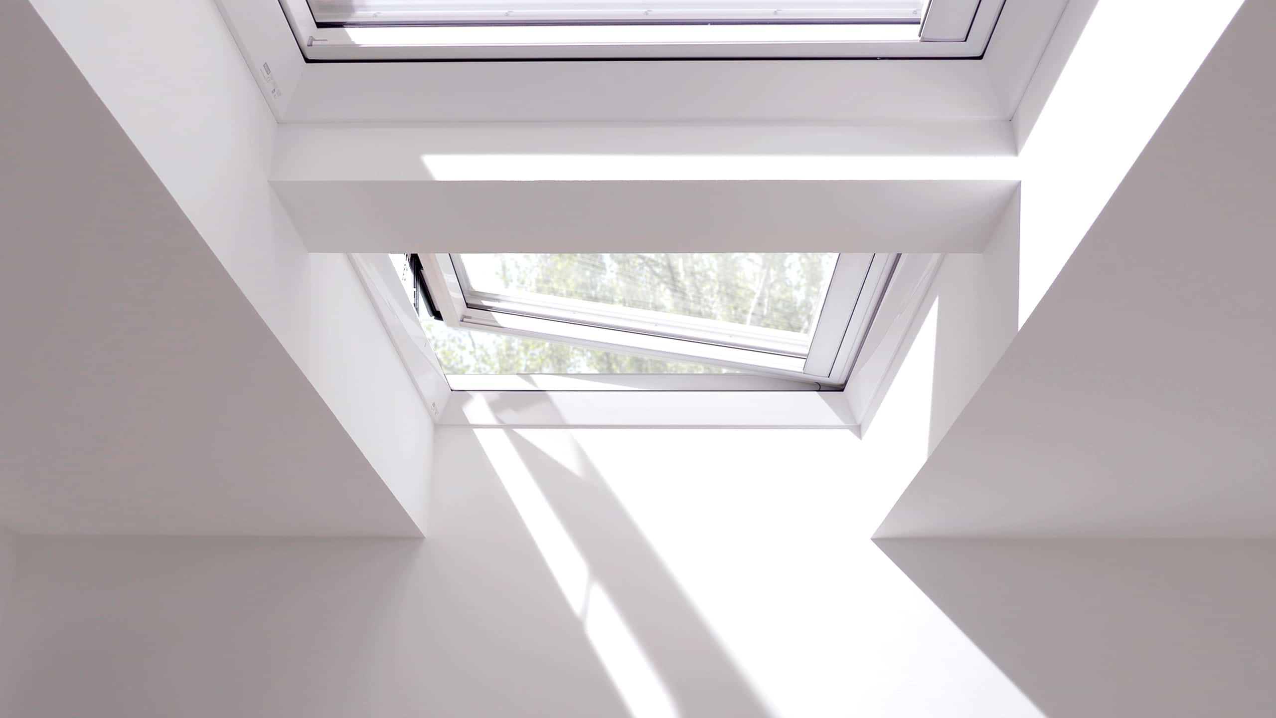 VELUX zeigt zwei Dachfenster auf einem Flachdach, die den Raum mit Licht durchfluten.