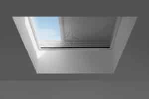 VELUX zeigt ein Dachfenster auf einem Flachdach mit weißer, lichtabschirmenden Beschattung.