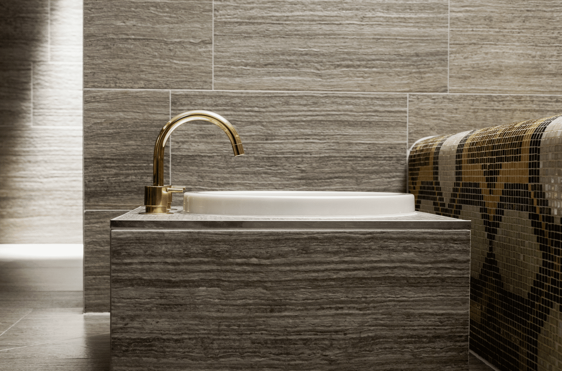 Gebogene Armatur in gold von VOLA über einem runden Waschbecken in einer Dampfsauna.