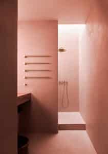 VOLA präsentiert ein Badezimmer mit Waschtisch und Duschnische mit Badezimmerheizung mit vier Stäben, Regendusche und Handbrause aus mattem Gold.