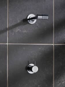 VOLA präsentiert eine Kopfbrause mit Eingriffbrausebatterie aus glänzendem Chrom an der Wand montiert.