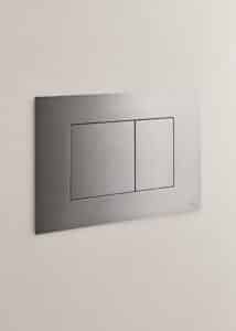 VOLA zeigt zwei eckige Spülauslöser in einem WC in mattem Chrom.
