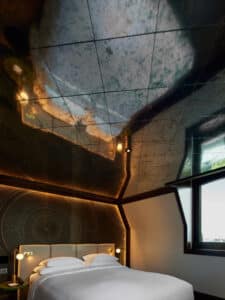 VOLA präsentiert ein elegantes Schlafzimmer in einem Hotelzimmer mit indirekt beleuchteter Rückwand und verspiegelter Zimmerdecke.