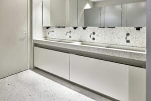 VOLA zeigt die Waschbecken einer öffentlichen WC-Anlage mit Armaturen und Sensoren aus chrom, die in der Wand integriert sind.