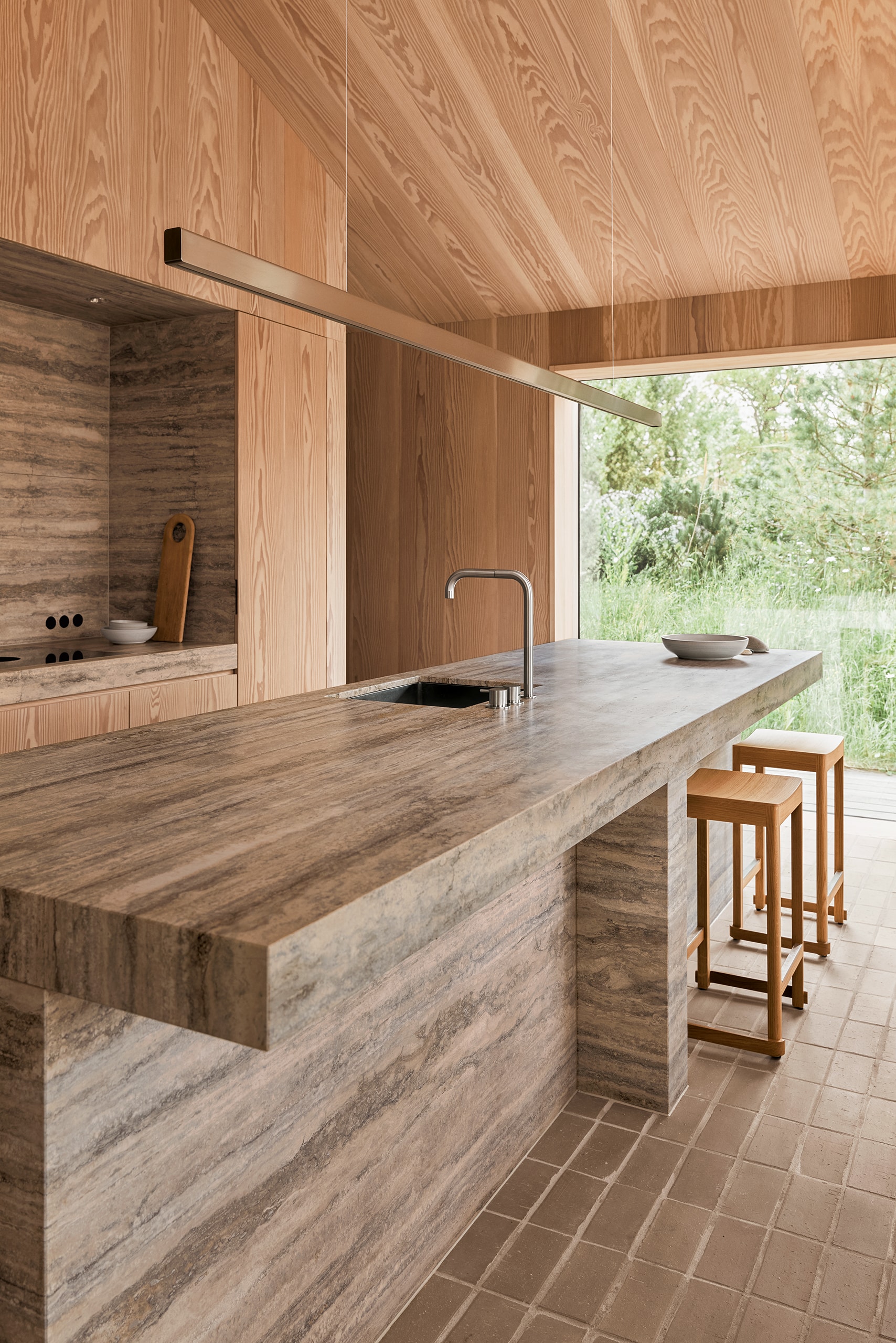 VOLA zeigt eine moderne Küche mit Marmor-Arbeitsplatte, flächenbündigem Waschbecken und einem Wasserhahn mit Schwanenhals in silber mit zwei Drehreglern, die auf der Arbeitsplatte montiert sind.