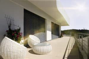 Ein Balkon mit Überdachung, bodentiefen Glaselementen mit außenliegenden, dunklen Jalousien von Warema.