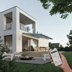 Ein modernes Flachdachhaus mit überdachtem Balkon, Terrasse, Outdoor‑Möbeln und per App gesteuerter Markise von Warema.