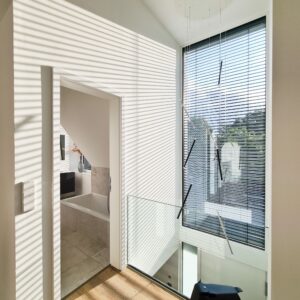 Ein modernes Haus mit Galerie, Dachschräge und großem Glaselement mit außenliegenden dunklen Jalousien von Warema.