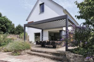 Eine anthrazitfarbene Lamellenpergola LAMAXA auf einer modernen Terrasse von WAREMA Sonnenschutz.