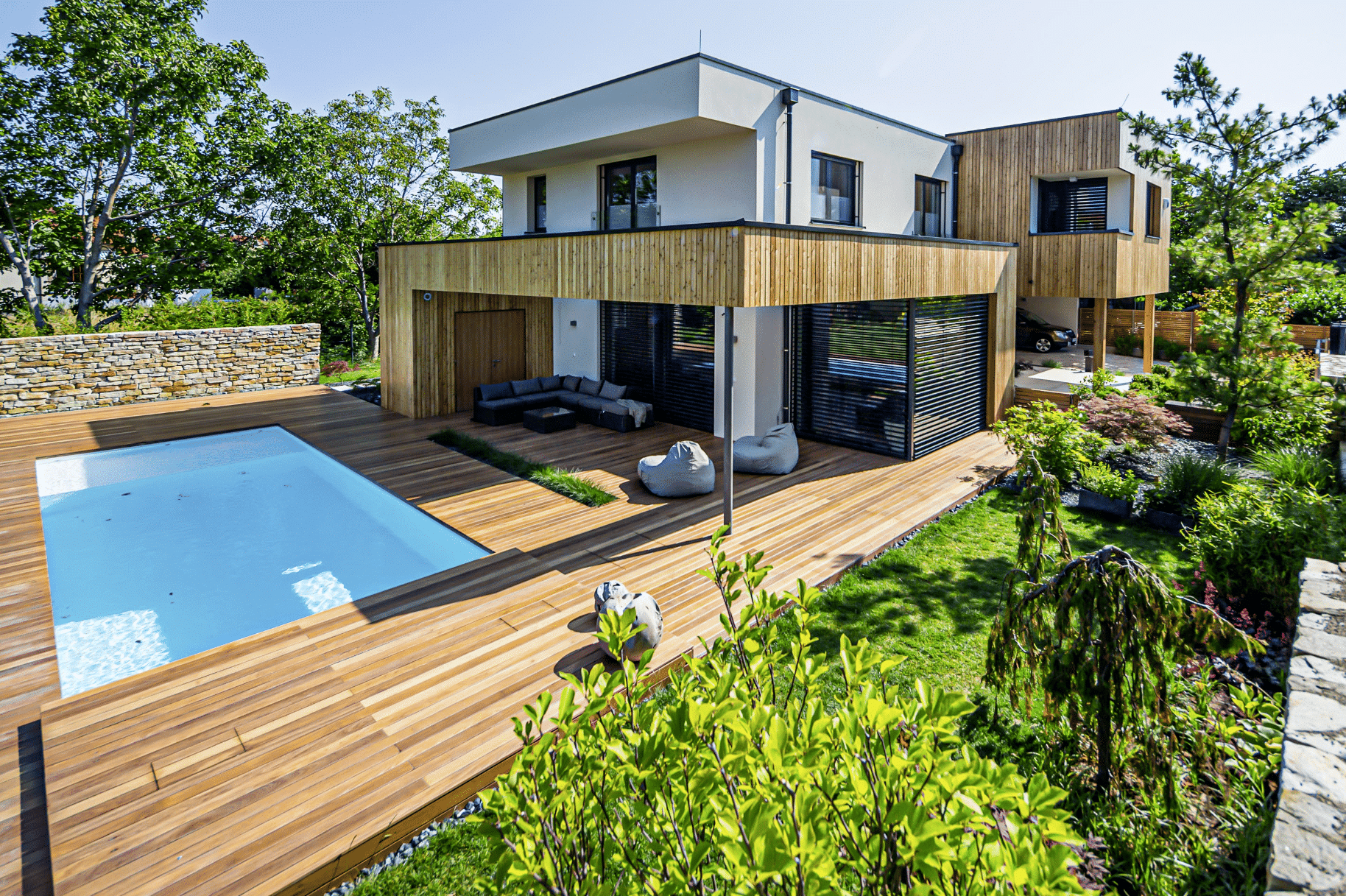 Einfamilienhaus mit Flachdach, Holzfassadenelementen, Terrasse, Balkon, Carport und Pool von Weissenseer Holz-System-Bau.