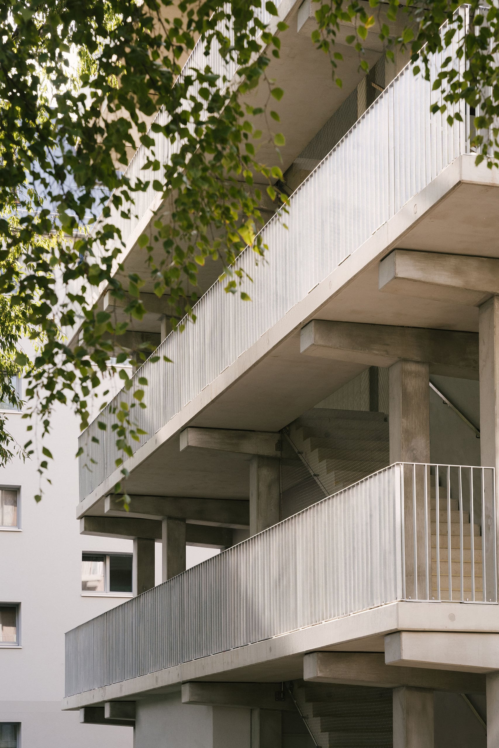 Weissenseer Holz-System-Bau zeigt ein Mehrparteienhauses in Berlin mit Holzfassade und überdachtem außenliegendem Treppenaufgang.