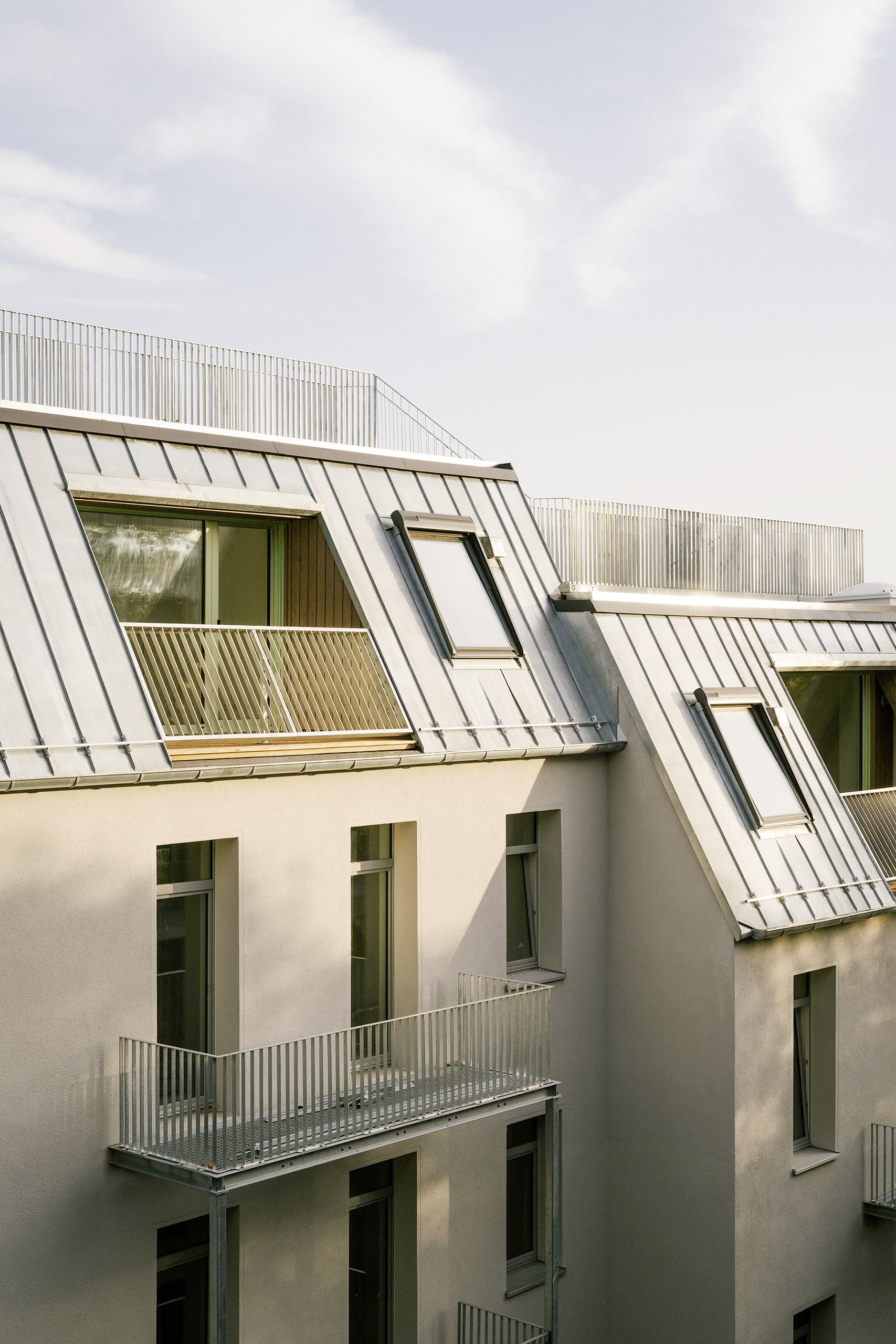 Weissenseer Holz-System-Bau zeigt ein Mehrparteienhauses in Berlin mit Satteldach, Balkon und Dachwohnung mit Dachterrasse.