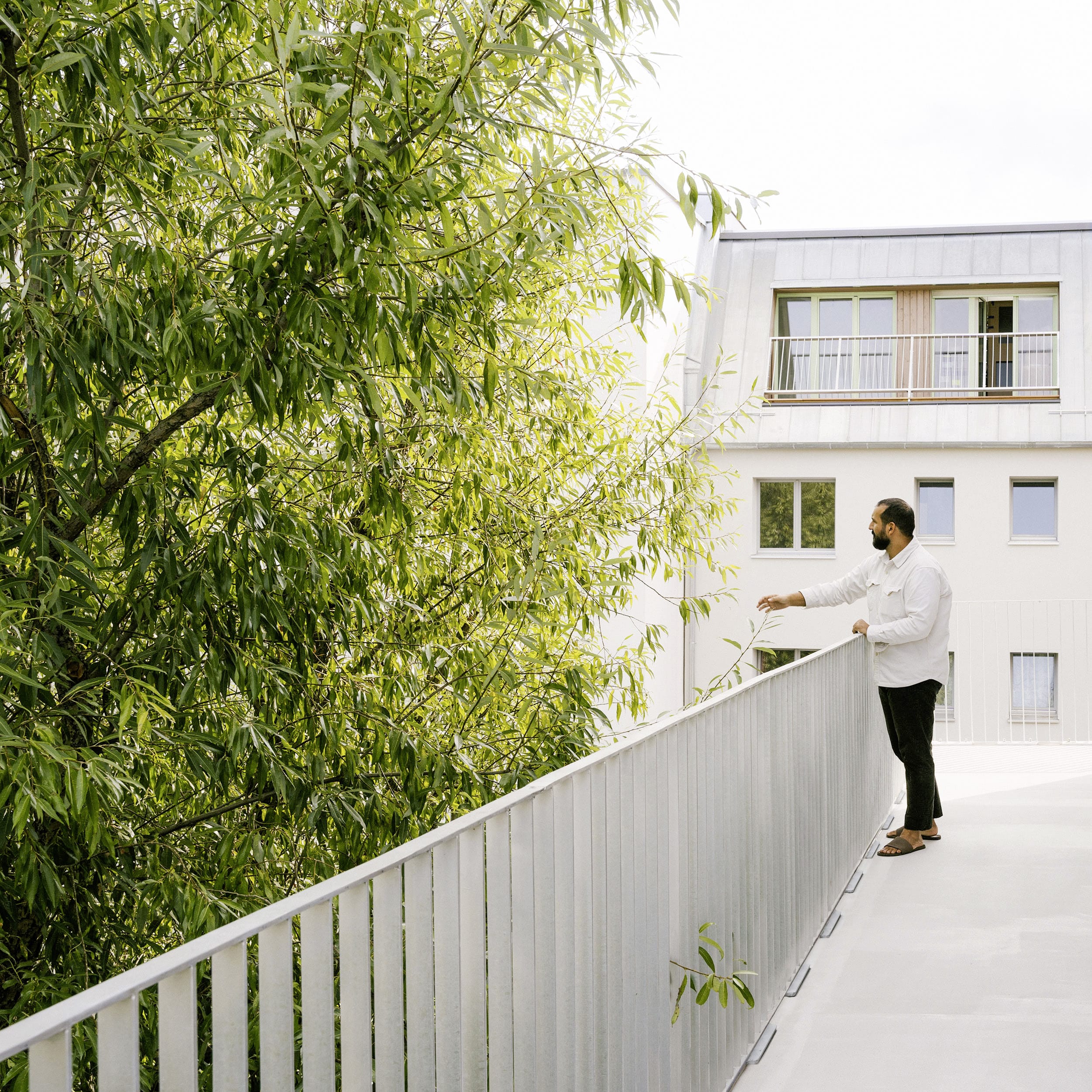 Weissenseer Holz-System-Bau zeigt einen Mann auf dem Balkon eines Mehrparteienhauses in Berlin.