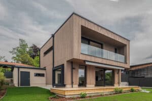 Ein modernes Einfamilienhaus mit Flachdach, Holzfassade, Terrasse, Balkon und Garten von Weissenseer.