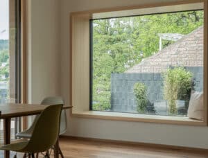 Ein offener Wohnbereich mit Holzrahmen‑Sitzfenster und Essbereich von Weissenseer.