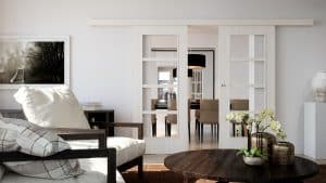 Wohnzimmer mit Blick in das Speisezimmer durch die zweiflügeligen Glasschiebetüren mit Schiebleiste, breitem Holzrahmen und Quersprossen in Weiss von WIENTÜR91.
