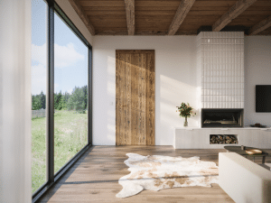 Wohnraum mit Terrassenschiebetüren, Kamin mit Holzlager, Holzdielen einem Fellteppich und einer rustikalen Holzdecke mit Balken und einer passenden Innenraumtüre im Altholz-Look und Türklinke in Bronze von WIENTÜR91.