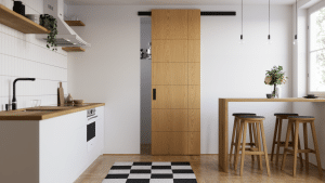 Küche mit schmaler Küchenzeile in Holz mit weissen Fronten, einem Baresstisch mit Hockern aus Holz und einer passenden Holzschiebetür zur Vorratskammer mit Ziernuten, mattschwarzem Einlassgriff und passender Laufschiene von WIENTÜR91.