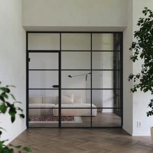 Loftartiger Wohnraum mit dunklem Fischgrätparkett und einer Glaswand mit Glastür zum Wohnbereich in mattschwarzem Sprossendesign und passenden Beschlägen und Türklinke von WIENTÜR91.