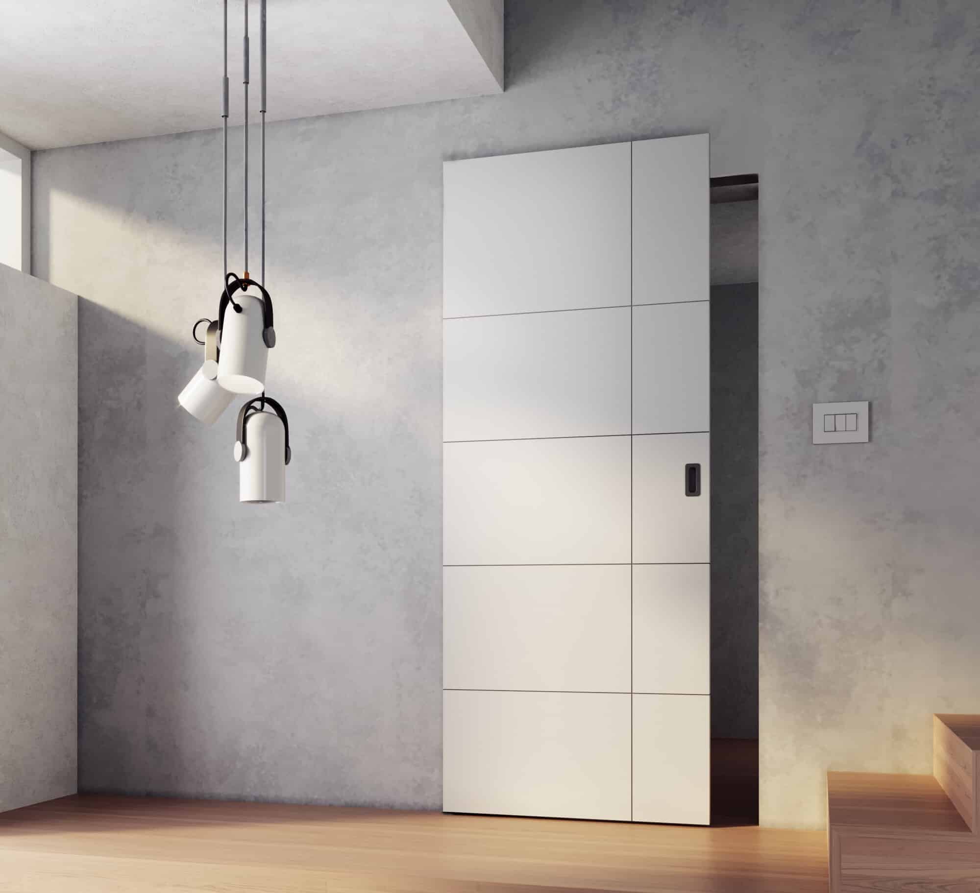 Eine an der Wand verlaufende Schiebetür von WIENTÜR91 by SAPELI mit unsichtbarer, türintegrierter Schiene, einem hellgrauen Türblatt, Parkettboden, einer Deckenleuchte im Bauhaus-Stil und Wänden in Betonoptik.